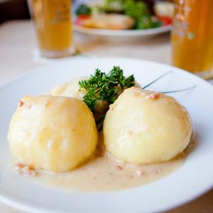 Zwei Saarländische Kartoffelklöße auf einem Teller mit Bier im Hintergrund 