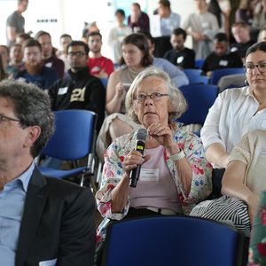 Person with Microphone in an audience on chairs