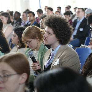 Person with Microphone in an audience sitting on chairs